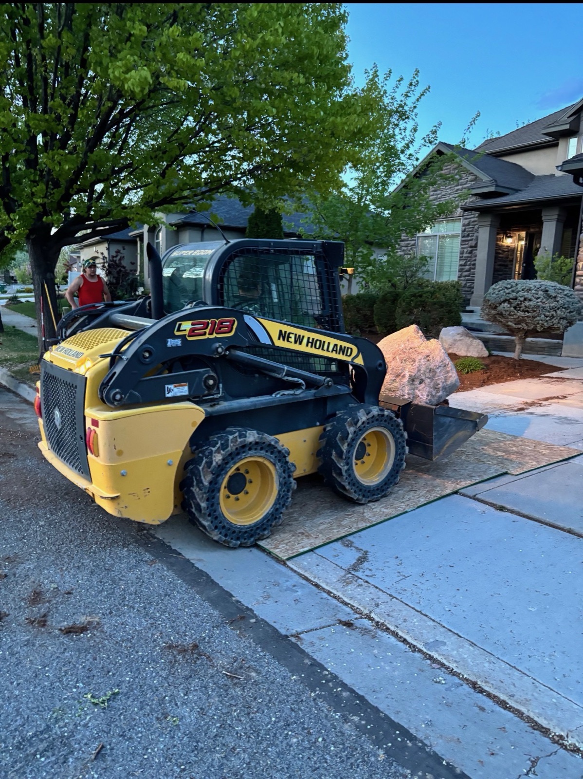 Skid steer loader moving rock at residential job site