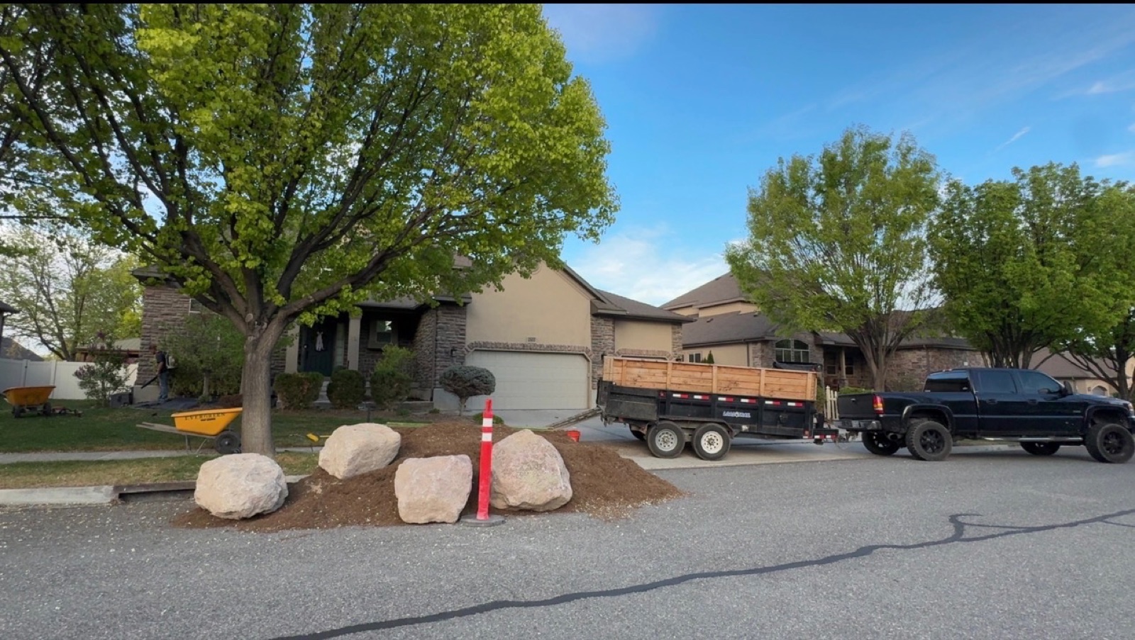 Boulders and rock install at front of home with company truck and dump trailer