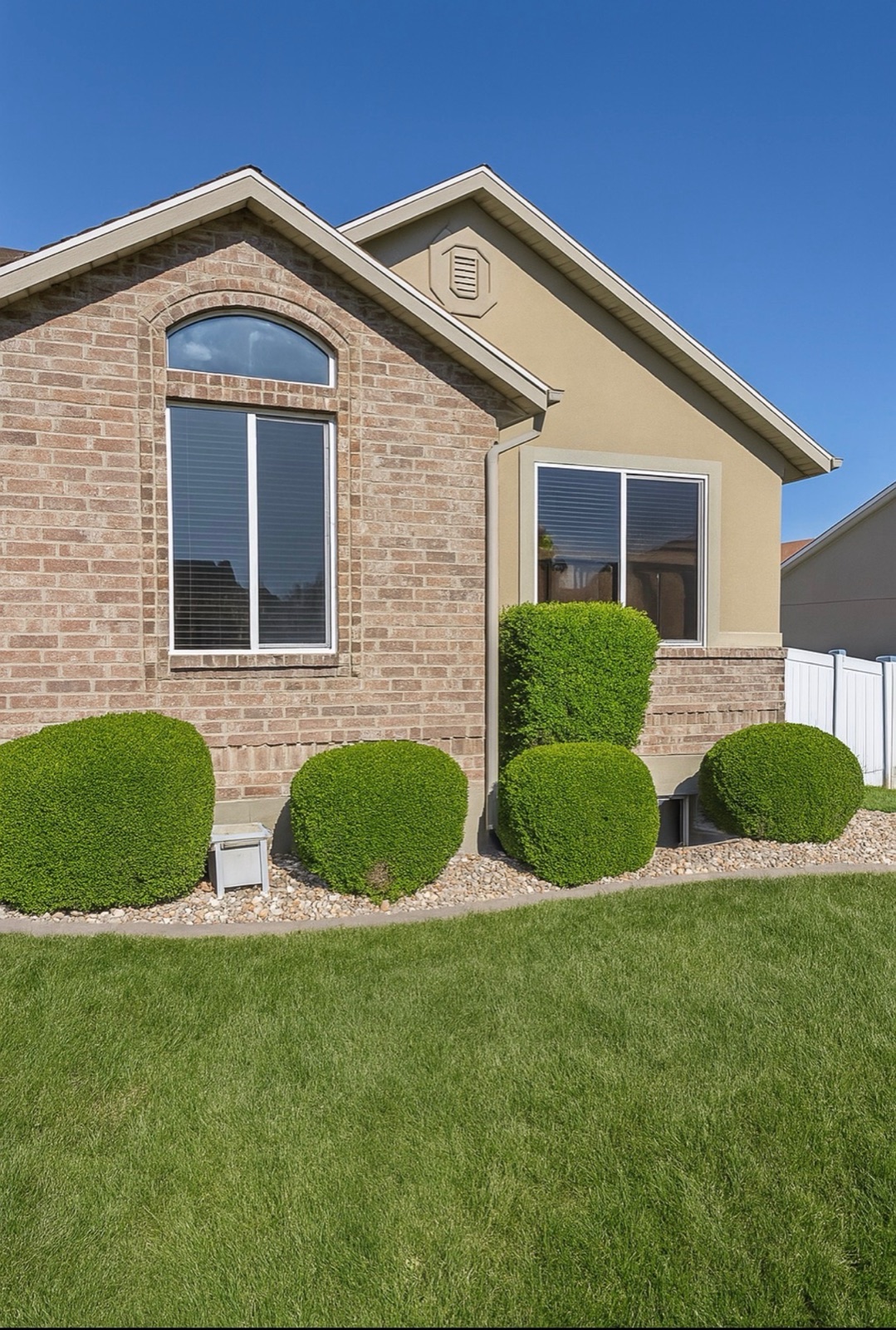 Manicured shrubs in front of brick home after landscape work